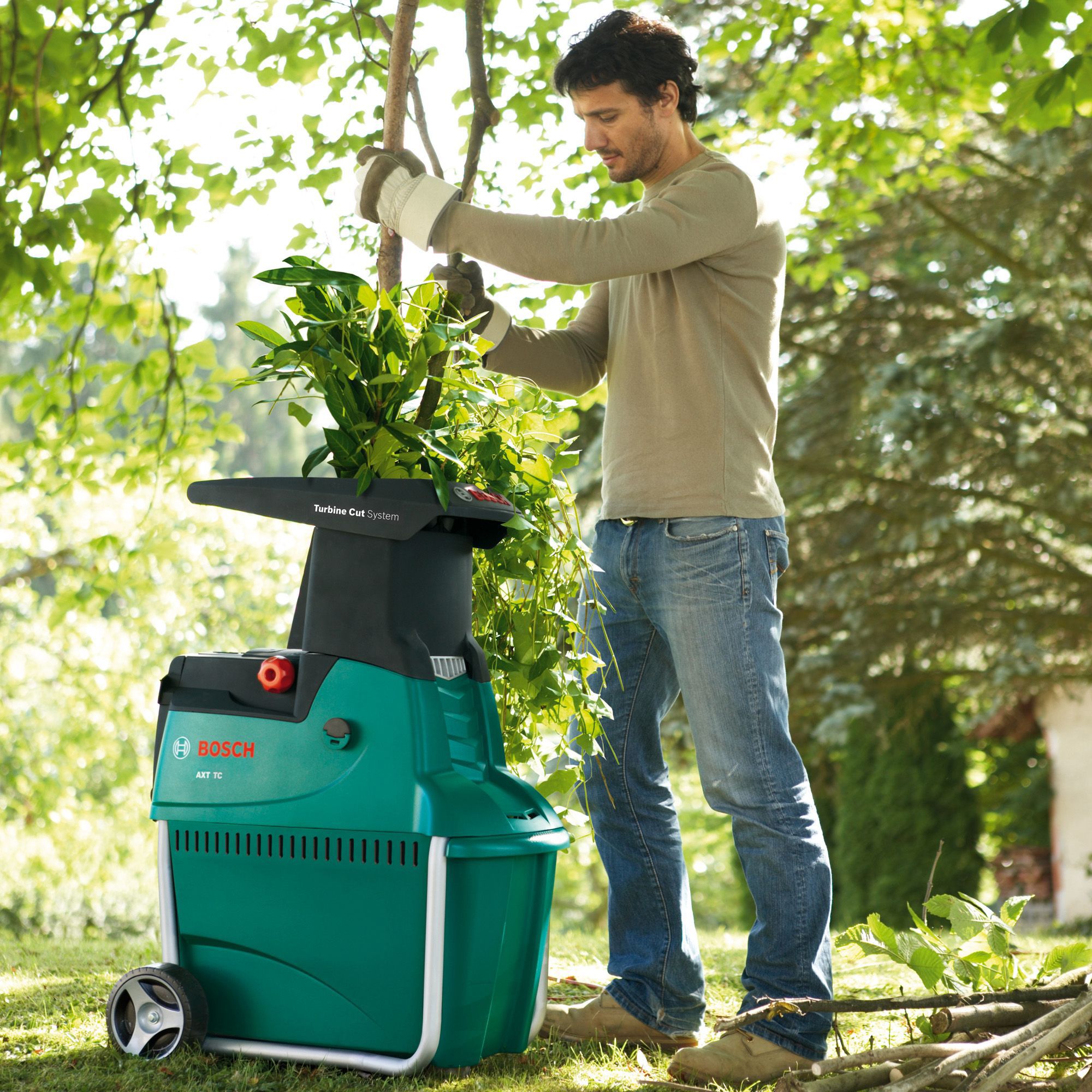 Person using a Bosch garden shredder to shred tree branches.