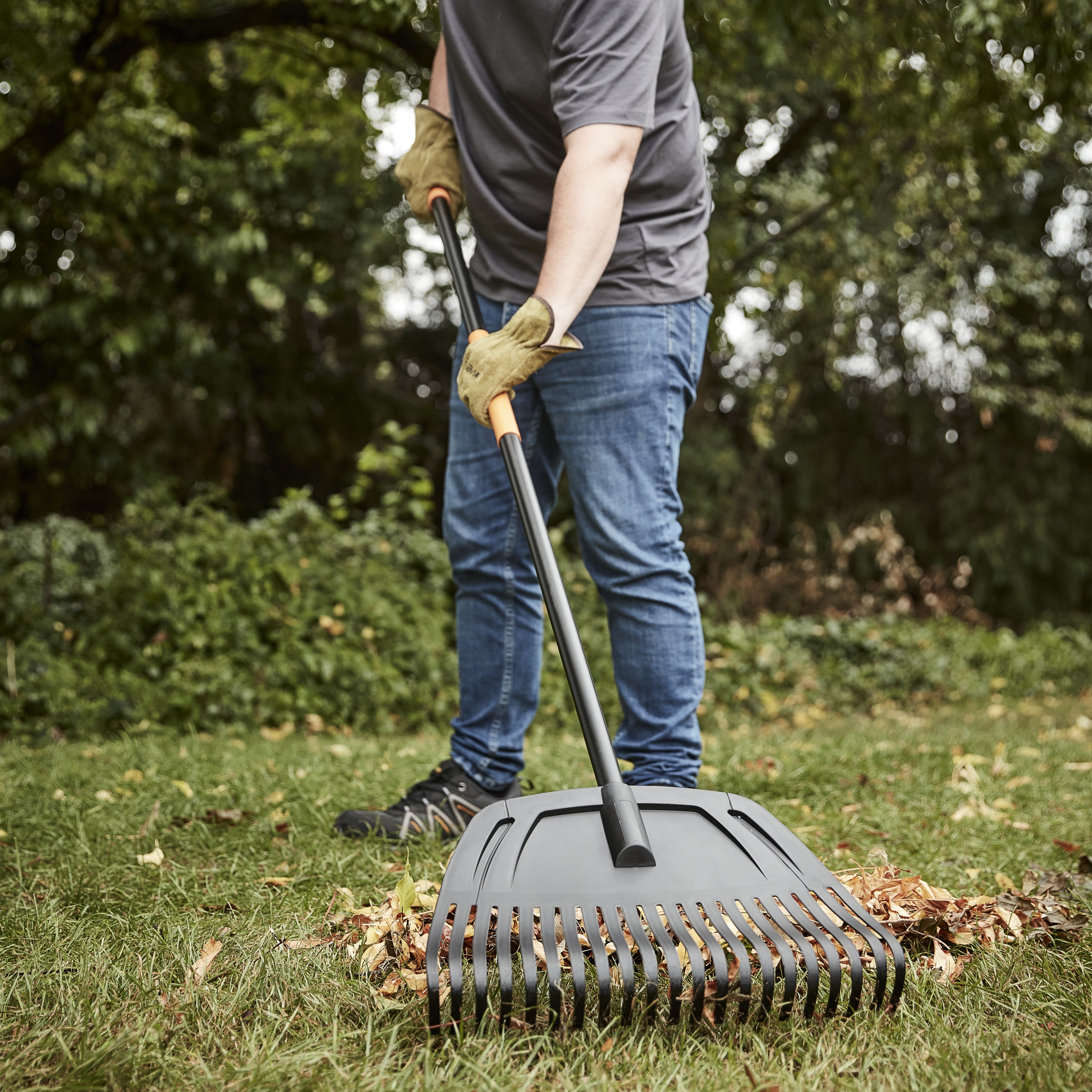 A Green Leaf Rake Lying On A Row Of Kraft Paper Leaf Bags Stock