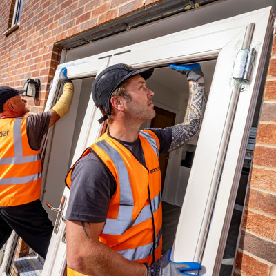 Tradesperson fitting  double glazed french doors into a house.
