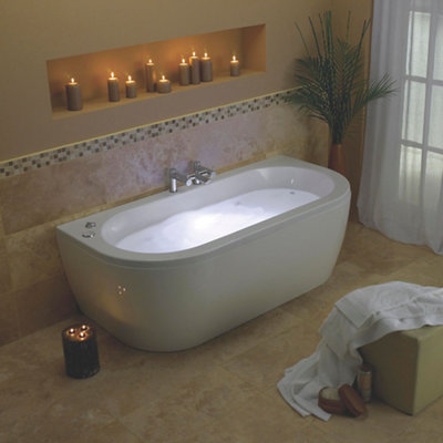 A spa bath with one side installed against a tiled wall with an alcove. Several candles have been lit in the alcove above the bath.