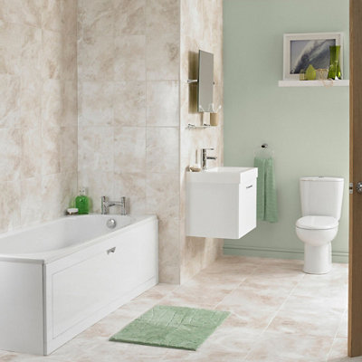 A straight bath installed against two walls in a bathroom with cream tiles and a green painted wall.