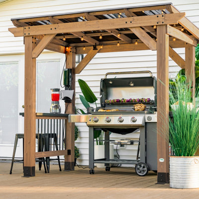 Wooden BBQ shelter covering an outdoor cooking and dining area