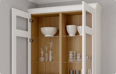 A wall-mounted kitchen cupboard has both doors open. The doors have a glass-front and there is a warm wood cupboard interior on display. Various glasses and bowls are on display in the cupboard.