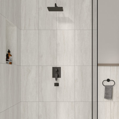 A shower enclosure with large, rectangular, textured light grey tiles.