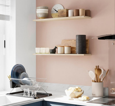 Pink kitchen with wooden floating shelves.