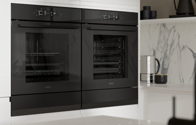 Gloss white kitchen with integrated handle design, featuring built-in black double ovens set against a marble-effect splashback.