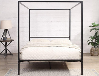 A black metal four-poster bed in a bright, modern bedroom.