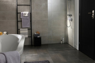 Textured grey floor and wall tiles in a bathroom with a walk in shower and freestanding bath tub.