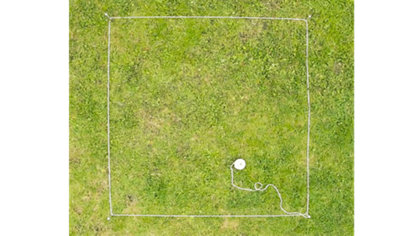 A square marked out on a lawn with pegs and a builders line to show where a sandpit will go.