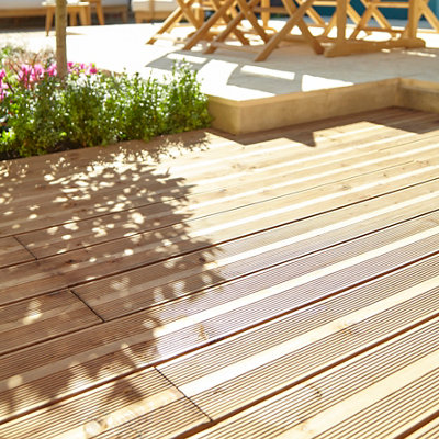 A light brown raised deck in a garden.