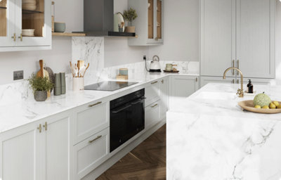 An L-shaped kitchen with shaker style, light grey cabinets, and a kitchen island enclosed in a white and grey marble-effect countertops. The kitchen countertop and splashback is also white and grey marble-effect.