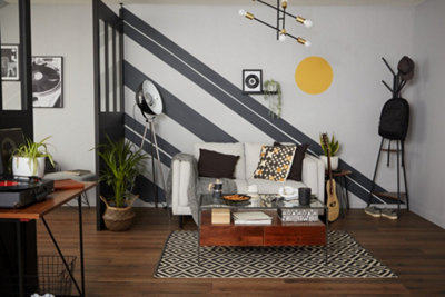 A modern white living room with striking black stripes painted on the wall going diagonally from the ceiling to the floor.