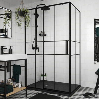 A black frame shower enclosure with a sliding door installed on a black shower tray in a white tiled bathroom.