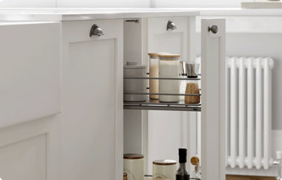 A pull-out larder cupboard displays condiments on grey shelves. The cupboard has a soft, creamy white, matt finished shaker style door front and a knob handle.