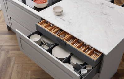 A light grey deep kitchen drawer is open to reveal various cooking pots and pans. The drawer has dividers for easier storage, and the drawer front has an integrated handle.