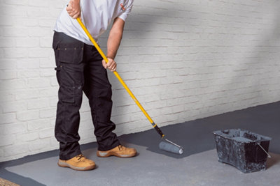 Person using a roller on an extendable pole to apply paint to a concrete garage floor.