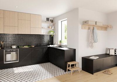 A kitchen with black base cabinets, light wood wall cabinets, and black and white floor tiles in a geometric pattern.