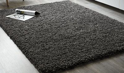 A soft grey high-pile rug on light grey wooden-effect laminate flooring.