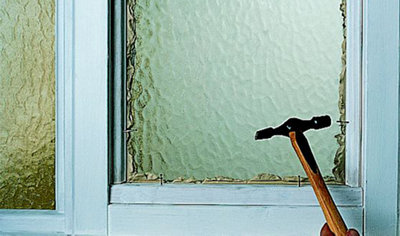 Person using a hammer to tap panel pins into the casement beads around the edge of a casement window frame.