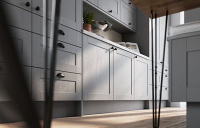 Low-angle view of a modern slate grey shaker kitchen with integrated storage cabinets, black cup handles, open shelving, white tiled splashback and natural wood flooring.
