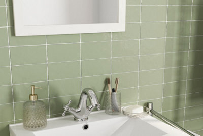 Mint green bathroom wall tiles behind a white basin with a chrome tap.