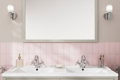 Pink metro tiles halfway up a wall behind a double basin unit in a bathroom.