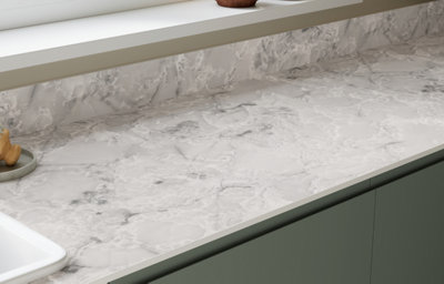 The Garcinia kitchen features matt slab doors with integrated handles in a soft green tone, paired with marble-effect worktops for a refined, modern finish.