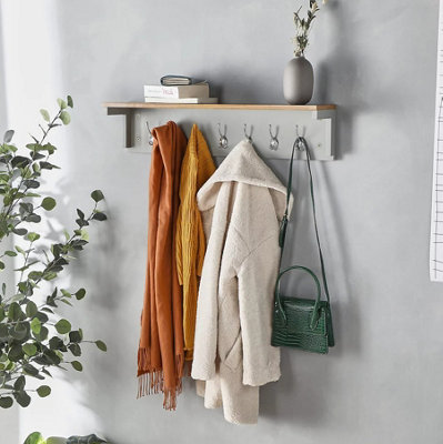 Grey wooden wall mounted rack and shelf with chrome hooks against a grey wall.