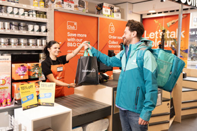 B&Q colleague handing a bag to a Deliveroo colleague.