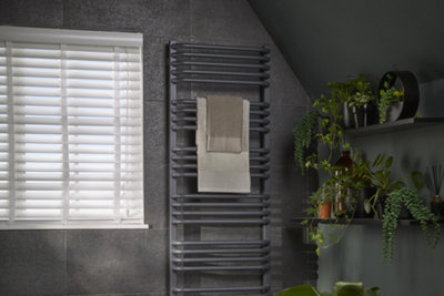 3 shelves with various bathroom plants installed under a sloped ceiling in a bathroom.