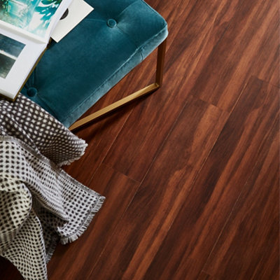 Dark wooden floorboards in a room with a teal chair and a black and white blanket.