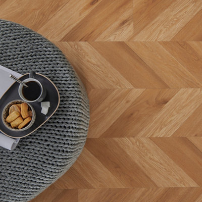 Wooden parquet flooring in a living room with a knitted footstool with a tray of tea and biscuits.