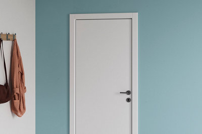 Blue hallway with a white door, next to which hangs a hanger with a coat and a bag.