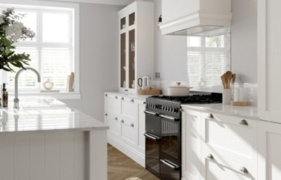 Porcelain white shaker kitchen with marble-effect worktops, island unit, range cooker and glazed display cabinet in a bright, contemporary setting.