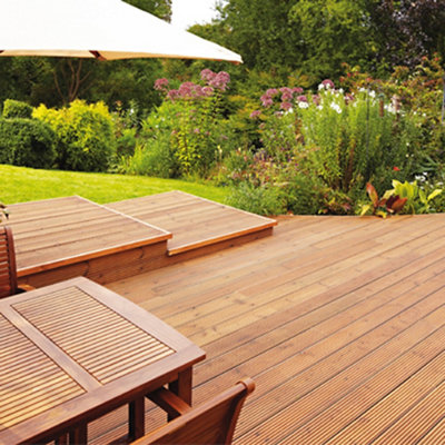 Garden decking with large steps, surrounded by a lush green lawn and large shrubs.