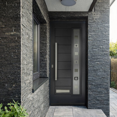 Modern dark grey made to measure door with long glass panel and steel handles and letterbox against dark grey slate door frame.