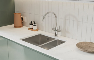 A close up of a gloss slab kitchen doors with integrated handles, white marble-effect worktop and integrated sink and silver tap