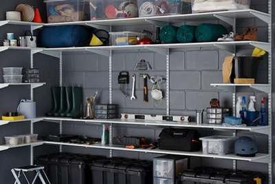 Workstation with workbench, tools hanging on the wall and shelving hanging various garage items.