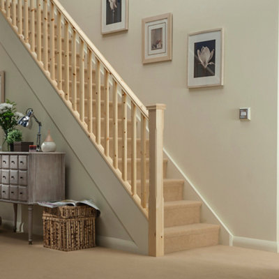 Staircase with a pine banister and cream carpeted steps.