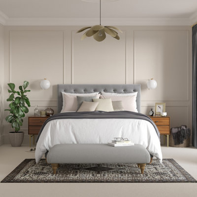 Neutral living room with wall panelling, a grey upholstered bed and a statement black and white patterned rug.