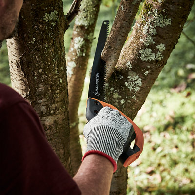 Small pruning saw being used to cut through a small tree branch.