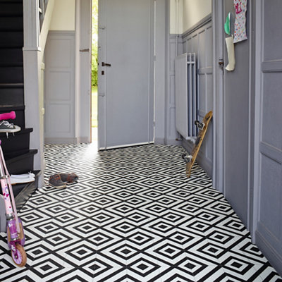 Black and white bold geometric patterned floor tiles in a hallway.