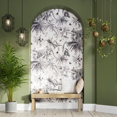 Green walls surround an arched wall with black and white animal-patterned wallpaper, with a wooden bench, a potted plant, hanging lamps, and hanging plants.