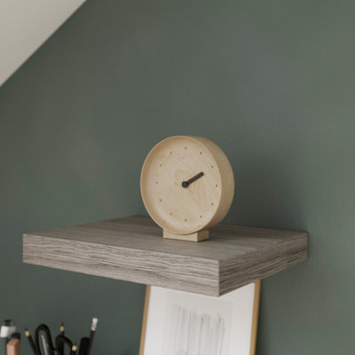Grey wooden effect small floating shelf with an alarm clock on it.
