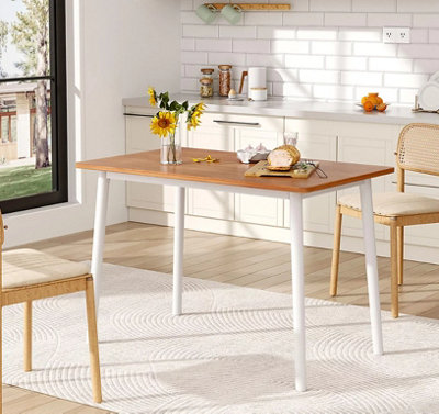 White and wooden Scandi style kitchen with a cream geometric print rug placed under a wooden dining table.