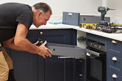 A tradesperson fitting a kitchen drawer in a new fitted kitchen.
