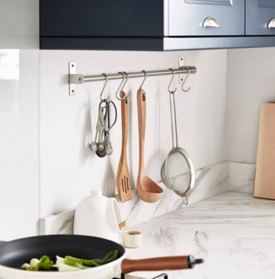Kitchen utensils hung from wall mounted kitchen rails and hooks.
