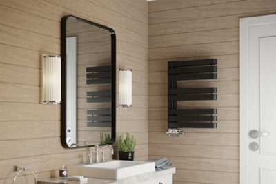 Black heated towel rail in a modern light brown bathroom.