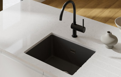 Gloss white slab kitchen with a minimalist island, featuring a black tap and sink set into a bright white marble-effect worktop.