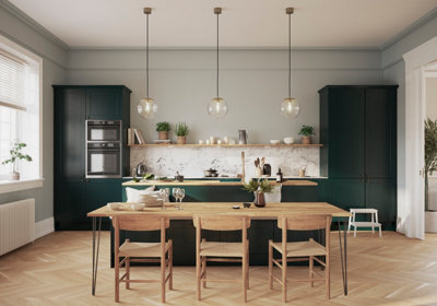 A large kitchen with green cabinetry and light wooden flooring in a herrigbone pattern.
